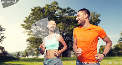 Image of smiling couple running over summer park background