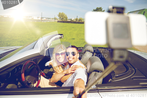 Image of happy couple in car taking selfie with smartphone