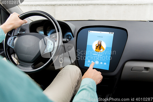 Image of man driving car with music on board computer