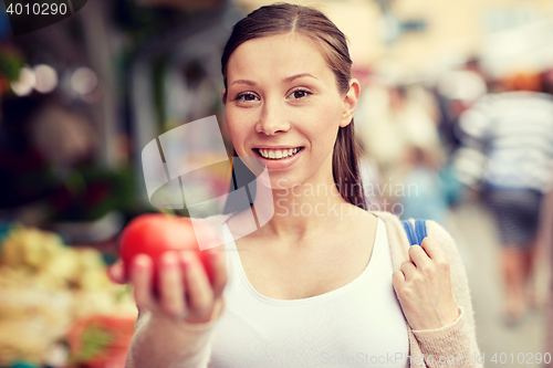 Image of happy woman holding tomato at street market