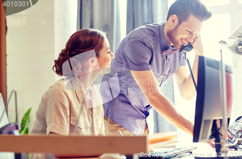 Image of happy creative team calling on phone in office