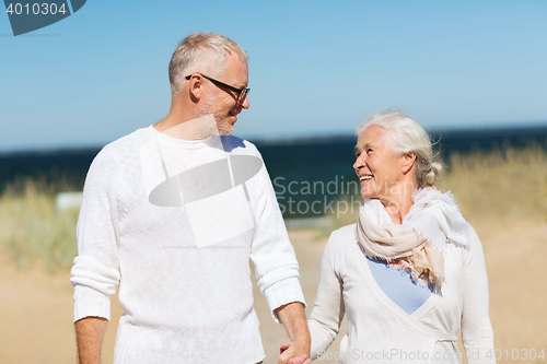 Image of happy senior couple holding hands on summer beach