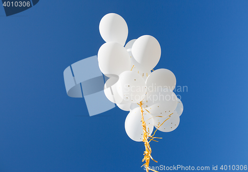 Image of close up of white helium balloons in blue sky