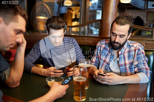 Image of men with smartphones drinking beer at bar or pub