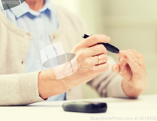 Image of senior woman with glucometer checking blood sugar