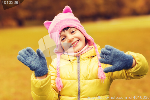 Image of happy beautiful little girl waving hands outdoors