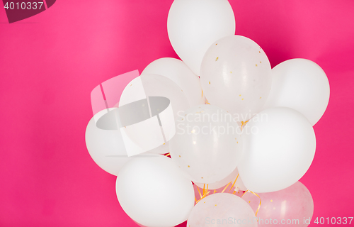 Image of close up of white helium balloons over pink