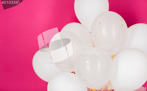 Image of close up of white helium balloons over pink