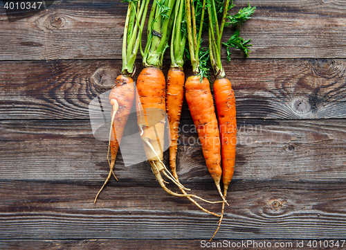 Image of Raw carrot with green leaves on wooden background