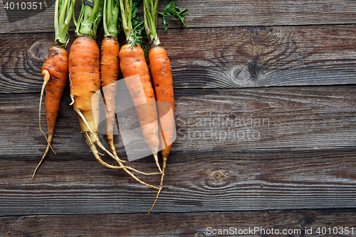 Image of Raw carrot with green leaves on wooden background