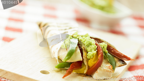 Image of delicious wrap tortilla with spicy chicken vegetables guacamole