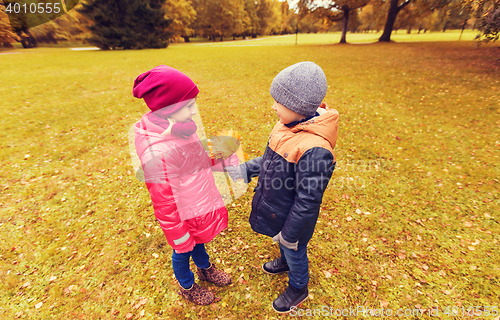 Image of little boy giving autumn maple leaves to girl