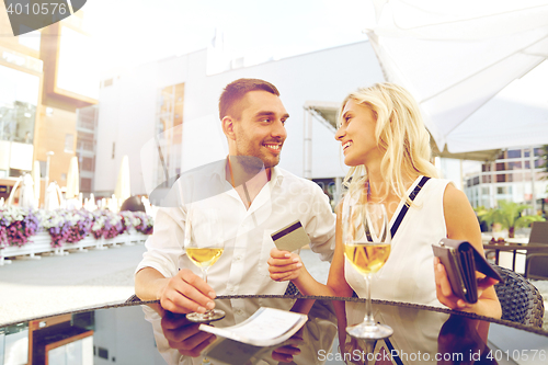 Image of happy couple with wallet paying bill at restaurant