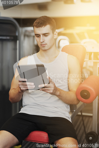 Image of young man with tablet pc computer in gym