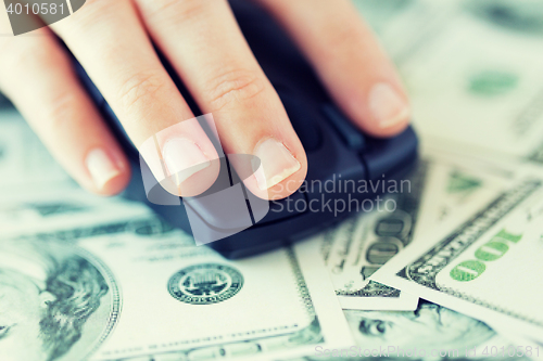 Image of close up of hand with computer mouse on money