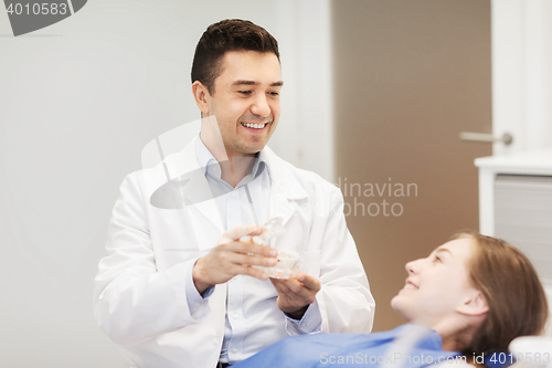 Image of happy dentist showing jaw layout to patient girl