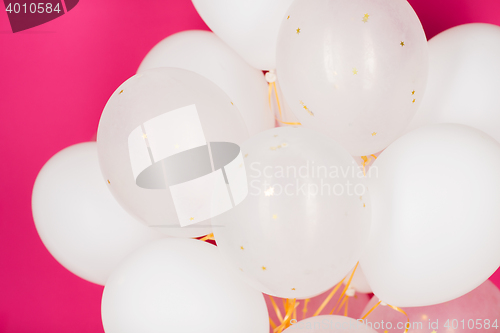 Image of close up of white helium balloons over pink