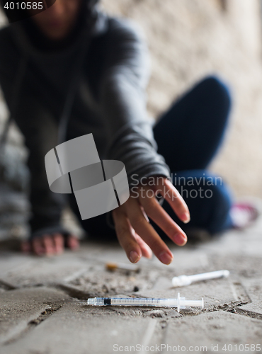 Image of close up of addict woman reaching to drug syringes