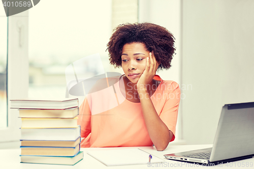 Image of bored african american woman doing homework home