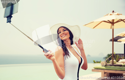 Image of happy woman taking selfie with smartphone on beach