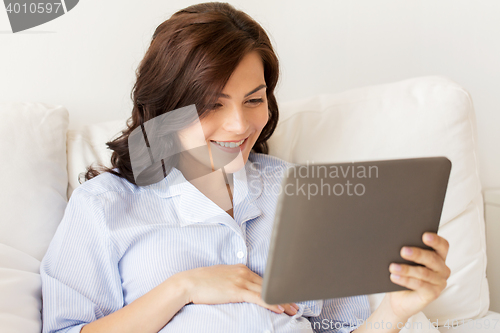 Image of happy pregnant woman with tablet pc at home
