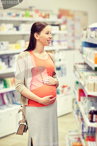 Image of happy pregnant woman choosing medicine at pharmacy