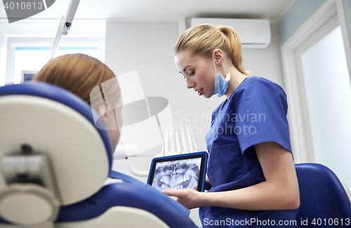 Image of dentist showing x-ray on tablet pc to patient girl