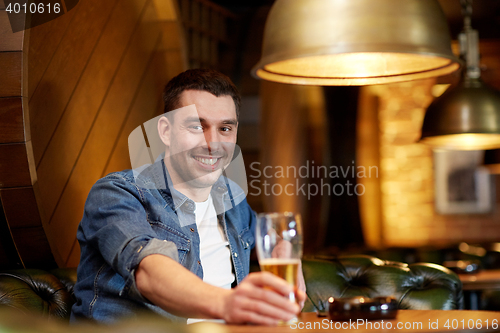 Image of happy man drinking draft beer at bar or pub