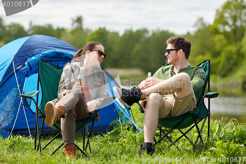 Image of happy couple drinking beer at campsite tent