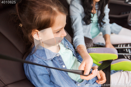 Image of happy woman fastening child with seat belt in car