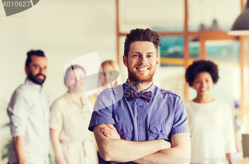Image of happy young man over creative team in office
