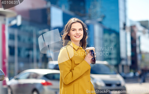 Image of happy young woman drinking coffee on city street