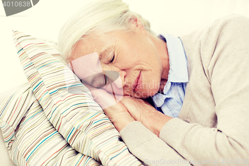 Image of happy senior woman sleeping on pillow at home