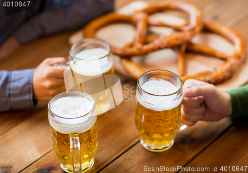 Image of close up of hands with beer mugs at bar or pub