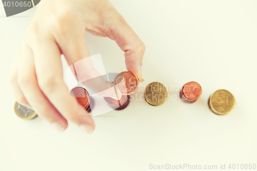 Image of close up of female hand putting coins into columns