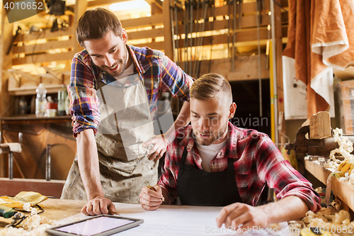 Image of workmen with tablet pc and blueprint at workshop