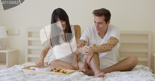 Image of Young couple having breakfast in bed