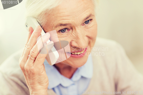 Image of senior woman with smartphone calling at home