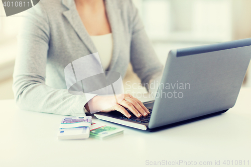 Image of close up of woman hands with laptop and money