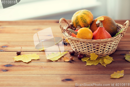 Image of close up of pumpkins in basket on wooden table