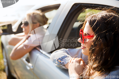 Image of happy teenage girls or women in car at seaside