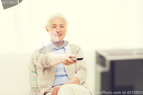 Image of happy senior woman watching tv at home