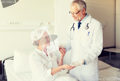 Image of doctor giving medicine to senior woman at hospital