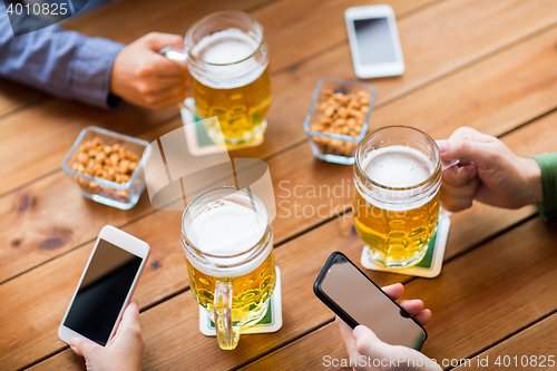 Image of close up of hands with smartphones and beer at bar