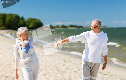 Image of happy senior couple holding hands on summer beach