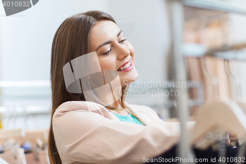 Image of happy young woman choosing clothes in mall