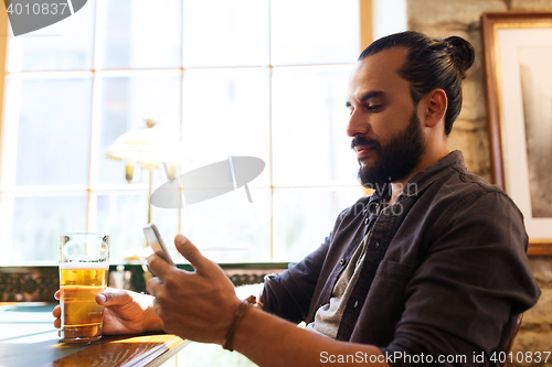 Image of man with smartphone drinking beer at bar or pub