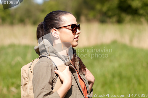 Image of happy young woman with backpack hiking outdoors