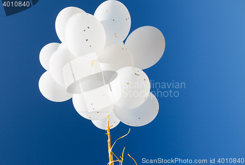 Image of close up of white helium balloons in blue sky