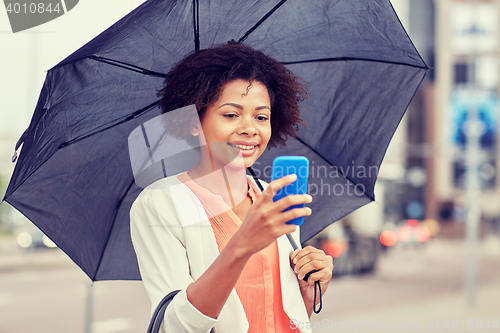 Image of businesswoman with umbrella texting on smartphone